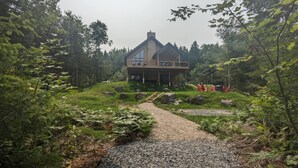 Een modern huis met een groot terras, omgeven door dicht bos.