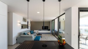 A modern living room with a sofa, a coffee table, and a TV. There is a large window and a balcony visible. - Lovely apartment in Rovanjska (Rovanjska)