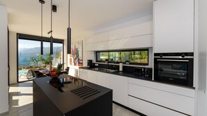 A modern kitchen with a large island, a built-in oven, and a view of the sea. - Lovely apartment in Rovanjska (Rovanjska)