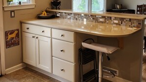 A kitchen with a large island, white cabinetry, a hanging light fixture, and a stained glass window. - 4 minutes from Saratoga Racetrack, this home is clean & cozy, with private deck (Saratoga Springs)