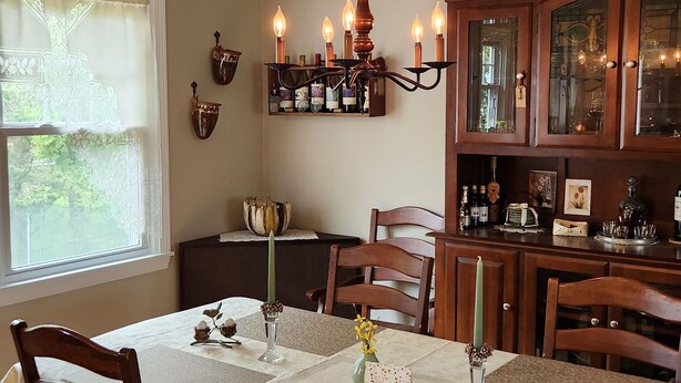 A dining area with a wooden table, chairs, a chandelier, and a wine rack. - 4 minutes from Saratoga Racetrack, this home is clean & cozy, with private deck (Saratoga Springs)