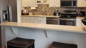 A modern kitchen with white cabinets, stainless steel appliances, and a stained glass light fixture. - 4 minutes from Saratoga Racetrack, this home is clean & cozy, with private deck (Saratoga Springs)