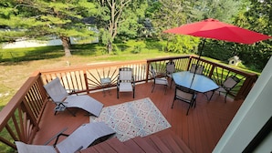 A wooden deck with a table and chairs, a red umbrella, and a patterned rug. - 4 minutes from Saratoga Racetrack, this home is clean & cozy, with private deck (Saratoga Springs)