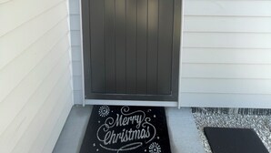 Une porte gris foncé, portant le numéro 9, avec un interphone et un paillasson sur lequel est écrit « Joyeux Noël », à l’entrée.