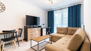 Ett modernt vardagsrum med en soffa, en tv, ett skrivbord och en stol.