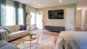 Un salon avec un canapé, une table basse et un téléviseur fixé au mur.