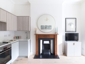A modern kitchen with a fireplace, a TV, and a dining area.