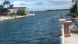 A waterfront view with a marina, a boat docked, and a building with a balcony. - Seabreeze Escape WF RV Lot 489 (Cudjoe Key)
