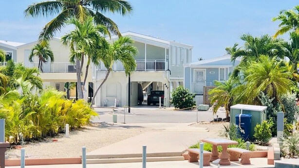 A beachfront property with a pool, palm trees, and a two-story building. - Seabreeze Escape WF RV Lot 489 (Cudjoe Key)