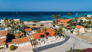 A coastal residential area with houses, palm trees, and a view of the ocean. - NEW Modern Cozy Studio Walking distance to Beach! (Noord)