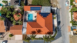 An aerial view of a residential property with a swimming pool, solar panels, and a tiled roof. - NEW Modern Cozy Studio Walking distance to Beach! (Noord)