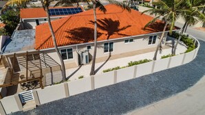 A modern building with a red-tiled roof, white walls, and a paved driveway. - NEW Modern Cozy Studio Walking distance to Beach! (Noord)