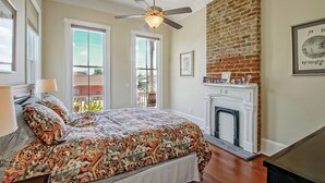 A bedroom with a bed, a ceiling fan, a fireplace, and a brick wall. - Historic Victorian in New Orleans, minutes from tourist attractions (New Orleans)