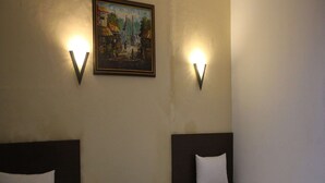Ett hotellrum med två separata sängar, en tavla på väggen och två vägglampor.