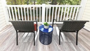 A balcony with two wicker chairs, a small round table with a plant, and a white railing. - Green Fairways Retreat Condo (Myrtle Beach)