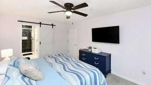 A bedroom with a bed, a ceiling fan, a TV, a dresser, and a door. - Green Fairways Retreat Condo (Myrtle Beach)