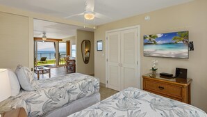 Une chambre d’hôtel avec deux lits, une télévision, une commode et une vue sur l’océan.