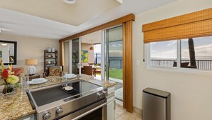Une cuisine moderne équipée d’une cuisinière en acier inoxydable, d’une porte en verre donnant sur un balcon et offrant une vue sur l’extérieur.