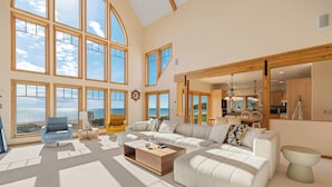 A spacious living room with large windows, a cozy seating area, and a view of the ocean. - Stunning Luxury Home on the Sandy Beach Shores of Lake Michigan!! (Sturgeon Bay)