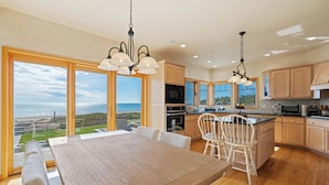 A modern kitchen with wooden cabinets, a large island, and a view of the ocean. - Stunning Luxury Home on the Sandy Beach Shores of Lake Michigan!! (Sturgeon Bay)