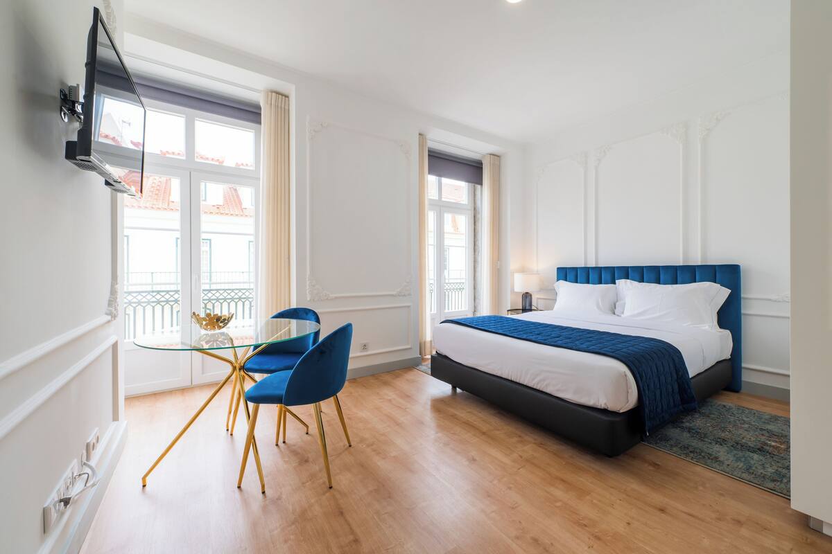 Ein Hotelzimmer mit einem Bett, einem Schreibtisch mit Stuhl und einem an der Wand befestigten Fernseher.