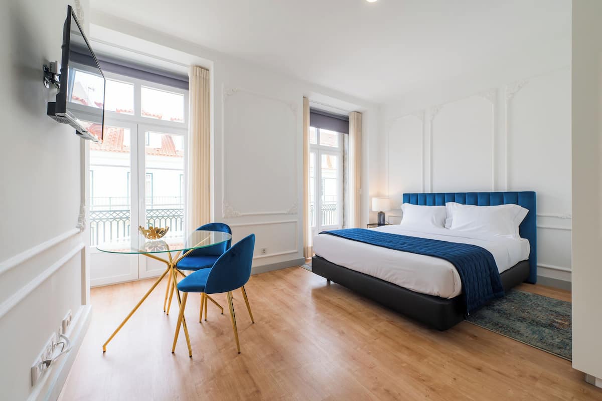 Una habitación de hotel con cama, escritorio con silla y televisor montado en la pared.