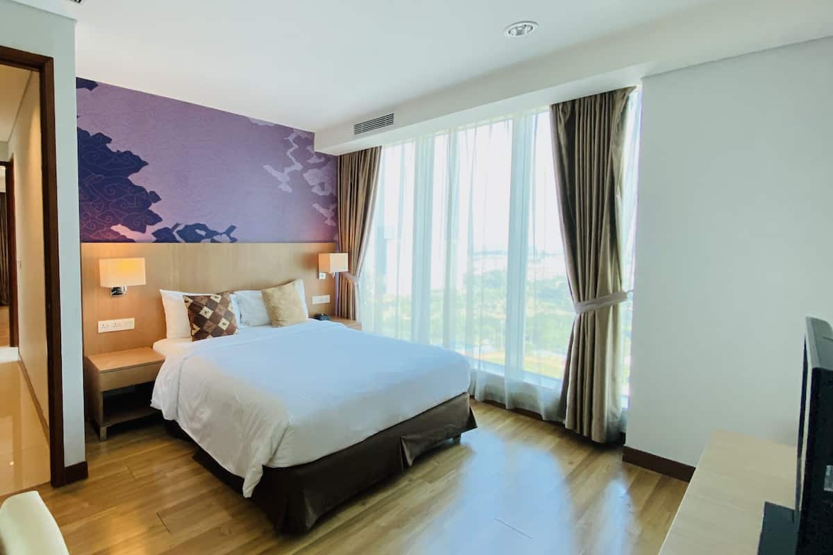 A hotel room with a large bed, a nightstand with a lamp, a view of the outdoors through large windows, and a modern wall design.