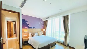 Quarto de hotel com uma cama grande, uma escrivaninha, uma cadeira, uma televisão e vista para o exterior.