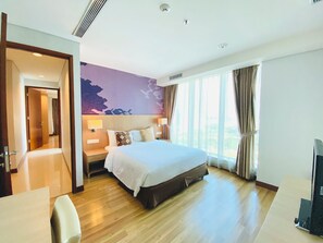 Quarto de hotel com uma cama grande, uma escrivaninha, uma cadeira, uma televisão e vista para o exterior.