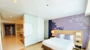 Quarto de hotel com uma cama grande, mesa de cabeceira com abajur, telefone e parede com padrão floral.