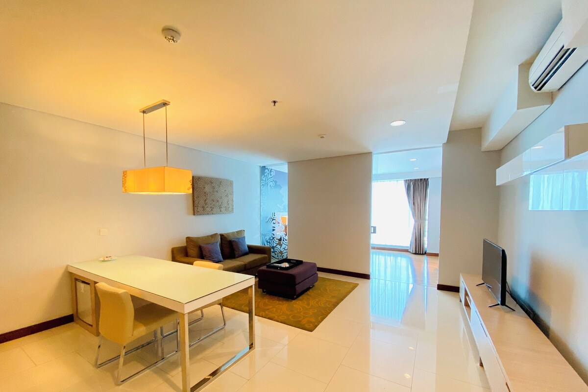 Uma sala de estar moderna com área de jantar, sofá, televisão e uma janela grande.