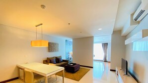 Uma sala de estar moderna com área de jantar, sofá, televisão e uma janela grande.