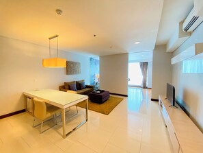 Uma sala de estar moderna com área de jantar, sofá, televisão e uma janela grande.