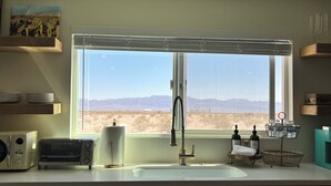 A kitchen with a large window, a sink, a toaster, and a paper towel holder.