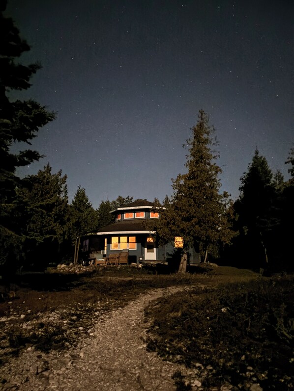 A house with a porch, a pathway leading to it, and a starry night sky.