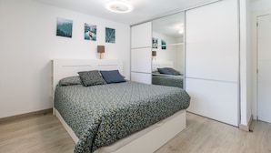 Een slaapkamer met een bed, een kledingkast en een spiegel.