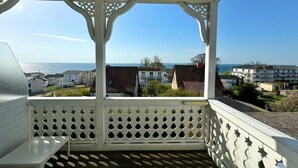 A covered outdoor area with a view of the sea and buildings.