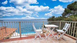 A balcony with a pool, white chairs, and a view of the sea. - Norbert by Interhome (Siracusa)
