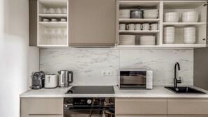 A modern kitchen with a built-in oven, a microwave, a sink, and a coffee maker. - Fabulous Meidling 2BR., Furnished & Equipped, by Blueground (Vienna)