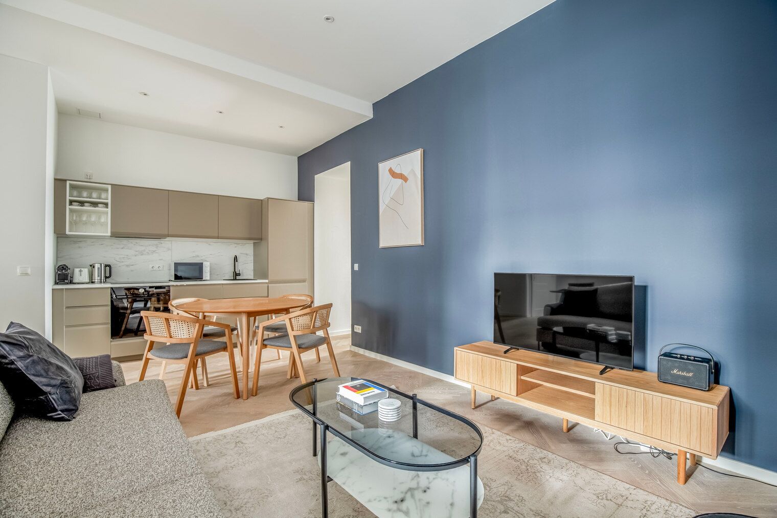Una sala de estar moderna con televisor, una mesa de centro y un comedor con mesa y sillas.