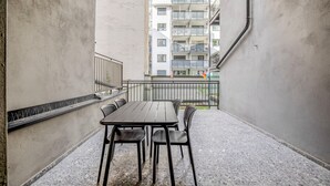 A balcony with a table and chairs, a metal railing, and a view of a multi-story building in the background. - Fabulous Meidling 2BR., Furnished & Equipped, by Blueground (Vienna)