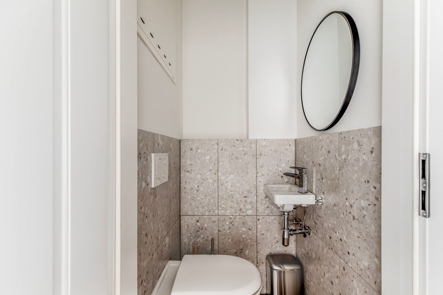 Une salle de bain moderne avec des toilettes sur pied, un lavabo fixé au mur et un grand miroir.