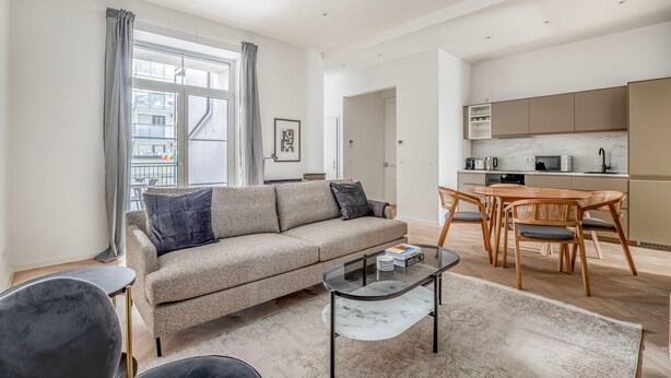 A modern living room with a sofa, coffee table, and dining area. - Fabulous Meidling 2BR., Furnished & Equipped, by Blueground (Vienna)