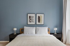 Une chambre à coucher comprenant un lit, deux tables de chevet et deux lampes fixées au mur.
