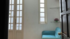 A room with a large window, a door, a blue sofa, and a wall-mounted air conditioner. - Minh Chau Hotel - Dien Bien Phu (Ho Chi Minh City)