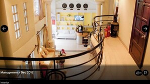 A spacious interior with a curved staircase, a living area with a sofa and armchairs, a chandelier, and a fireplace. - Minh Chau Hotel - Dien Bien Phu (Ho Chi Minh City)