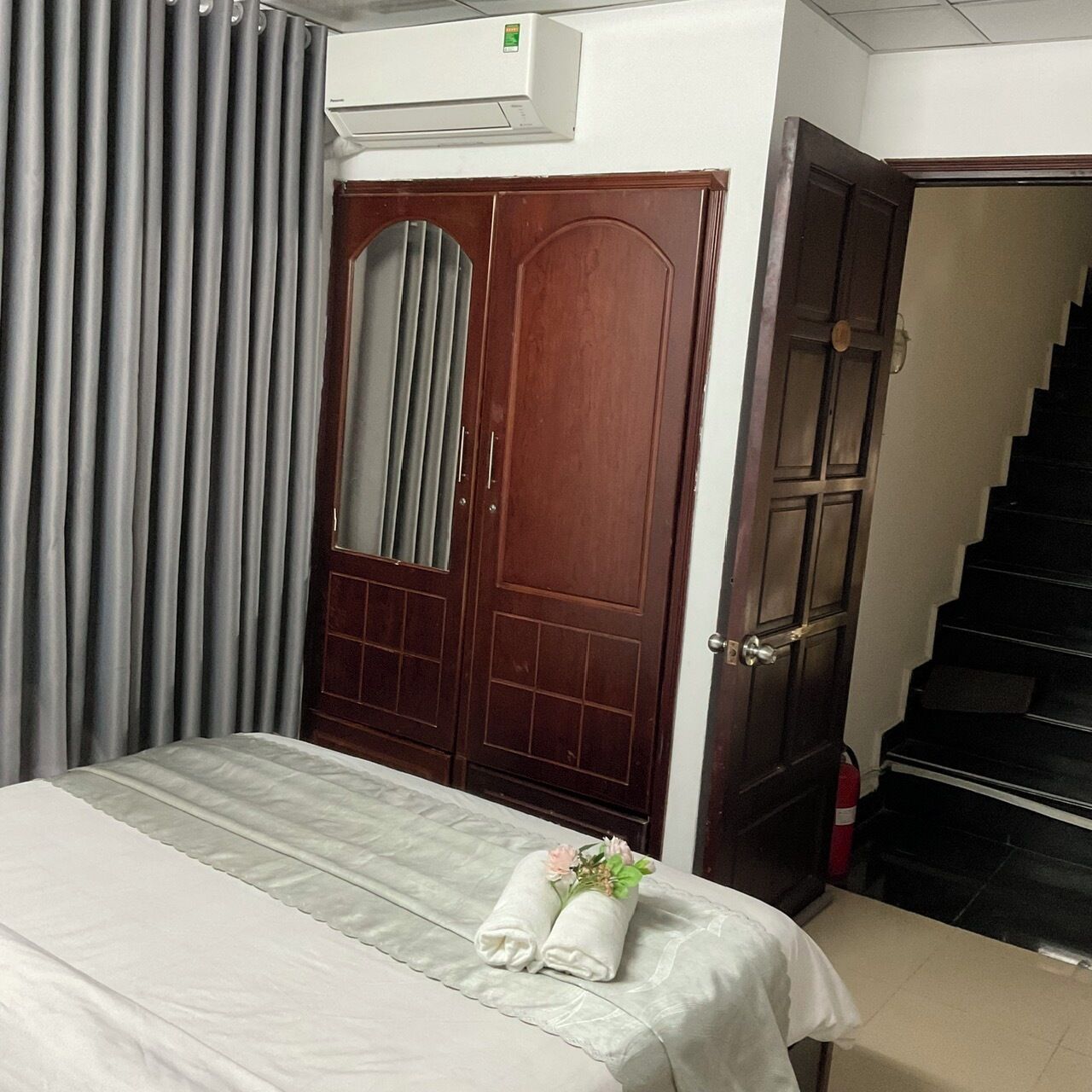 Une chambre d’hôtel avec un lit, une porte en bois, un escalier et un appareil de climatisation.