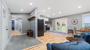 Eine moderne Küche mit weißen Schränken, einem schwarzen Kühlschrank und einer Mikrowelle. Ein Essbereich mit einem blauen Sofa und einem Holztisch.