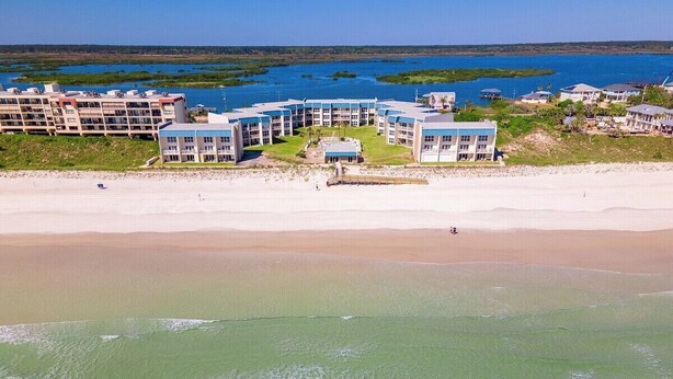 Et strandhotel med flere bygninger, en sandstrand og udsigt over havet.