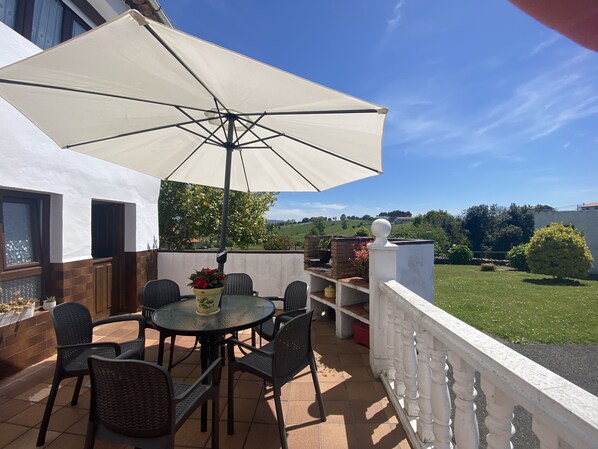 An outdoor patio with a round table, chairs, and a large umbrella. - Vivienda Vacacional La Mata Vieja (La Franca)